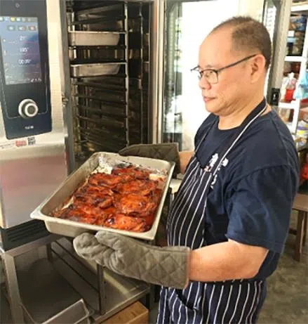 吴金宝在现有厨房学习烹煮红烧鸡肉。新厨房的面积将是现有的六倍，不仅能容纳更多学员接受培训，也有助提升餐饮产能。（突破宣道之家提供）