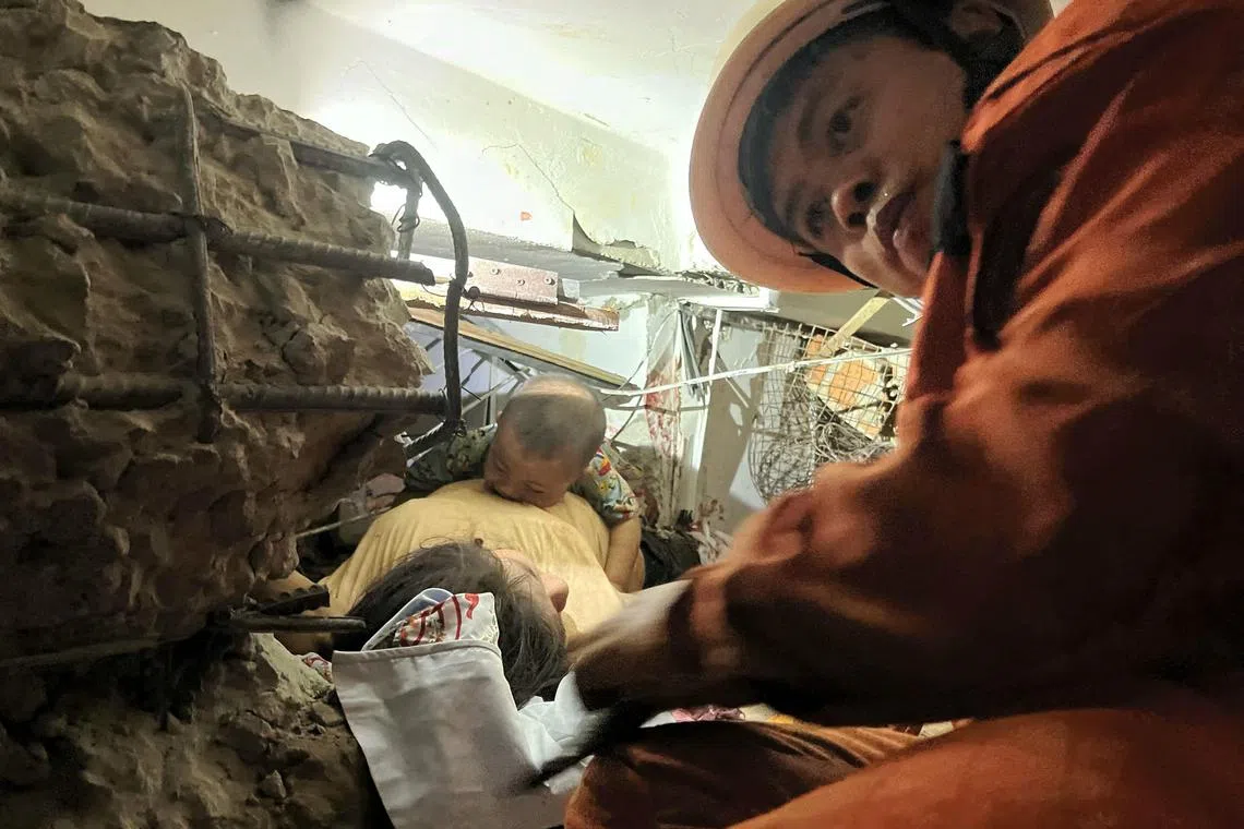 缅甸救援人员在曼德勒一栋倒塌的建筑内，营救一名受困的妇女和她的孩子。（法新社）