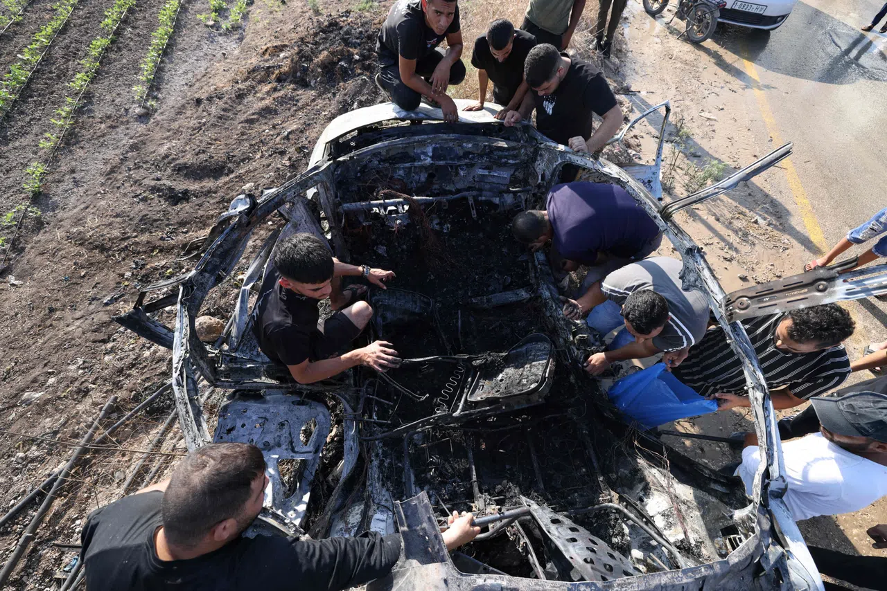 以色列星期六空袭约旦河西岸城市图勒凯尔姆一辆汽车，炸死五人，其中一人是哈马斯一名指挥官。事后一些巴勒斯坦人检查汽车残骸。（法新社）