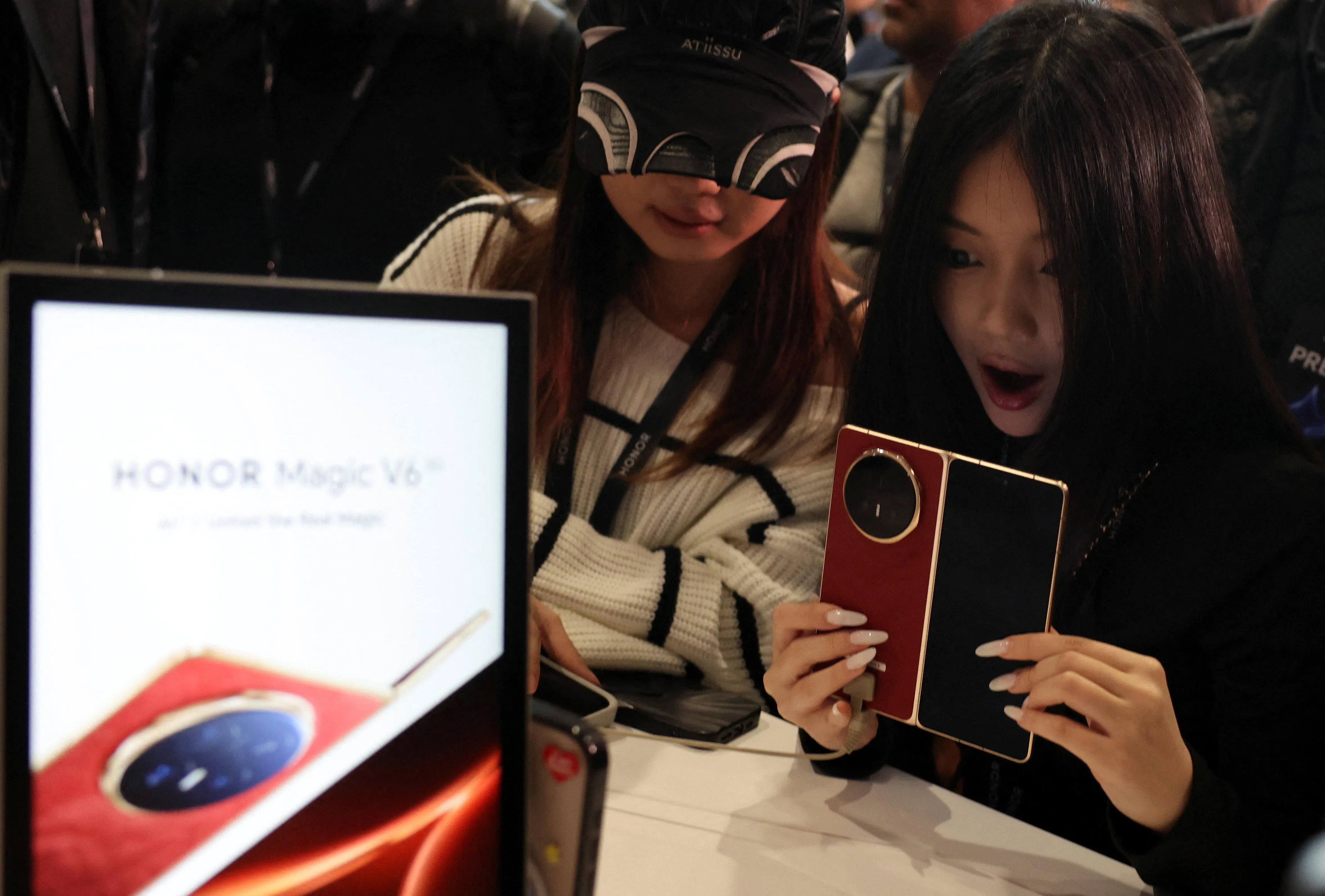 一名女子在MWC现场体验Magic V6，手机展开时厚度只有4毫米。（路透社）