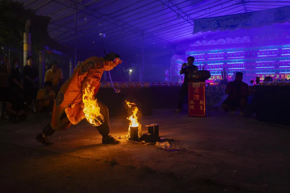 【破地狱六部曲】之一：师傅将口中含着的清水，喷向沸腾热油。（龙国雄摄）