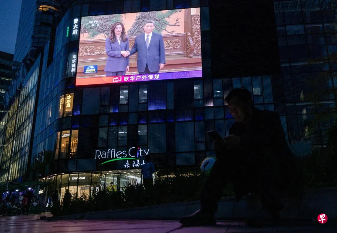 国共领导人睽违10年再度会谈，图为北京街头的巨型屏幕正在播放新闻，画面显示中国国家主席习近平（右）4月10日在北京人民大会堂，与台湾最大在野党党国民党主席郑丽文握手。 （路透社）