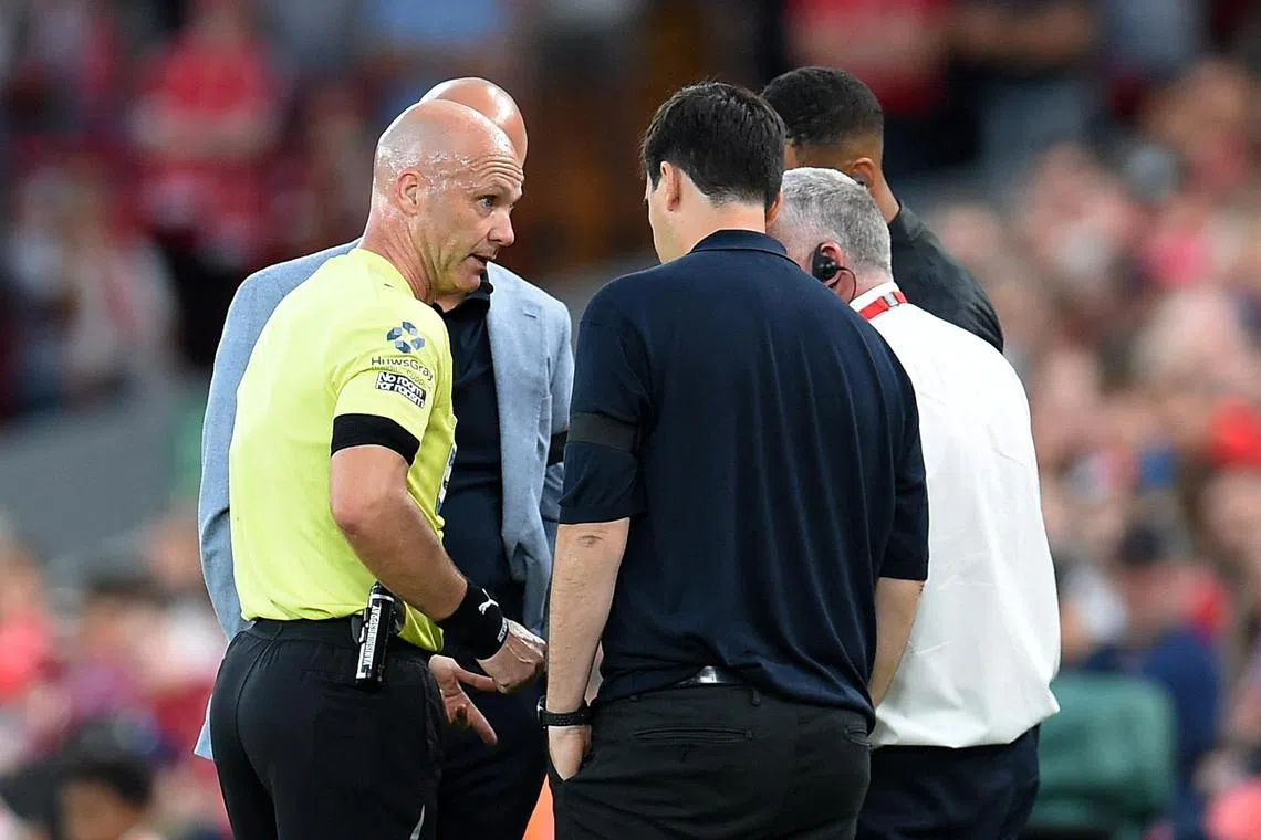 裁判泰勒（黄衣）在种族歧视事件发生后暂停比赛，并和两队教练进行了沟通。（路透社）