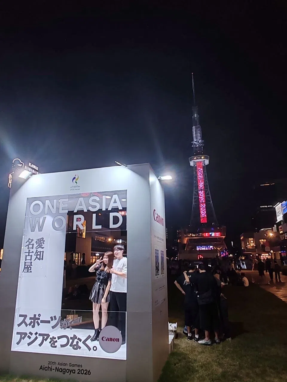 一对男女在中部电力塔附近举办的亚运会庆典活动中，以铁塔为背景，于照相区拍照。（陈明耀摄）