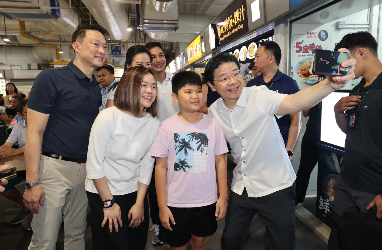黄循财总理（手持手机者）走访盛港一带时，与居民合照，站在他旁边的有盛港集选区基层组织顾问蓝彬明（左一）和黎曦怡（半蹲者）。黎曦怡背后站着盛港东支部主席王诗佳（半遮）和盛港集选区基层组织另一顾问埃尔米。（邬福梁摄）