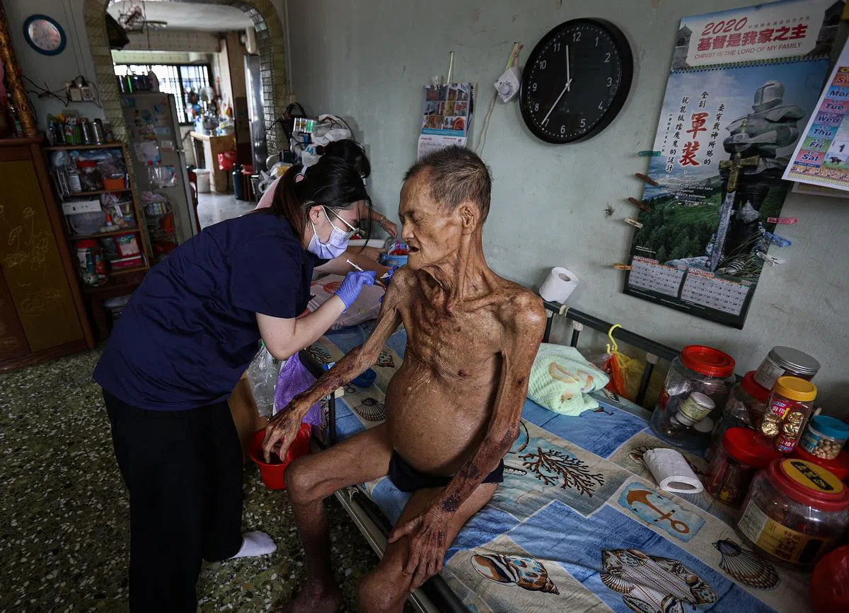 登门接种疫苗服务团队的护士黄千僡（左）到史密斯街的三房式组屋单位，为年长者辜文狮接种第一剂冠病疫苗。《联合早报》摄影记者李健玮的这张照片，在今年的亚洲新闻摄影大赛中，获得突发新闻组的银奖。（李健玮摄）