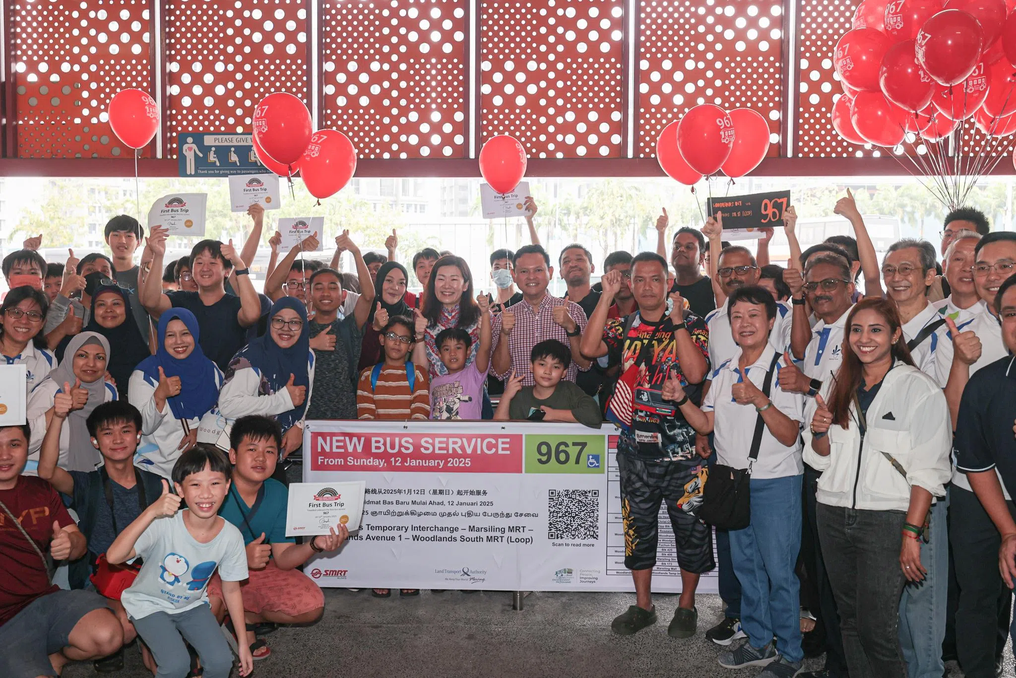 人力部兼国防部高级政务部长扎吉哈（正中格子上衣）及同是马西岭—油池集选区议员的苏慧敏（扎吉哈右侧）出席新环线巴士的启用推介活动，与上百名巴士发烧友和SMRT的工作人员及义工一起合照。（李冠卫摄）