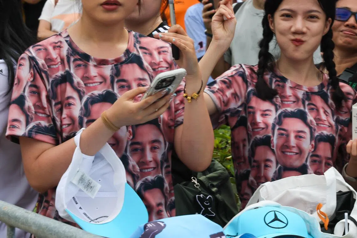 两位拉塞尔的支持者身穿印满这名英国车手脸庞的衣服。偶像在新加坡夺冠，想必她们非常开心。（张俊杰摄）