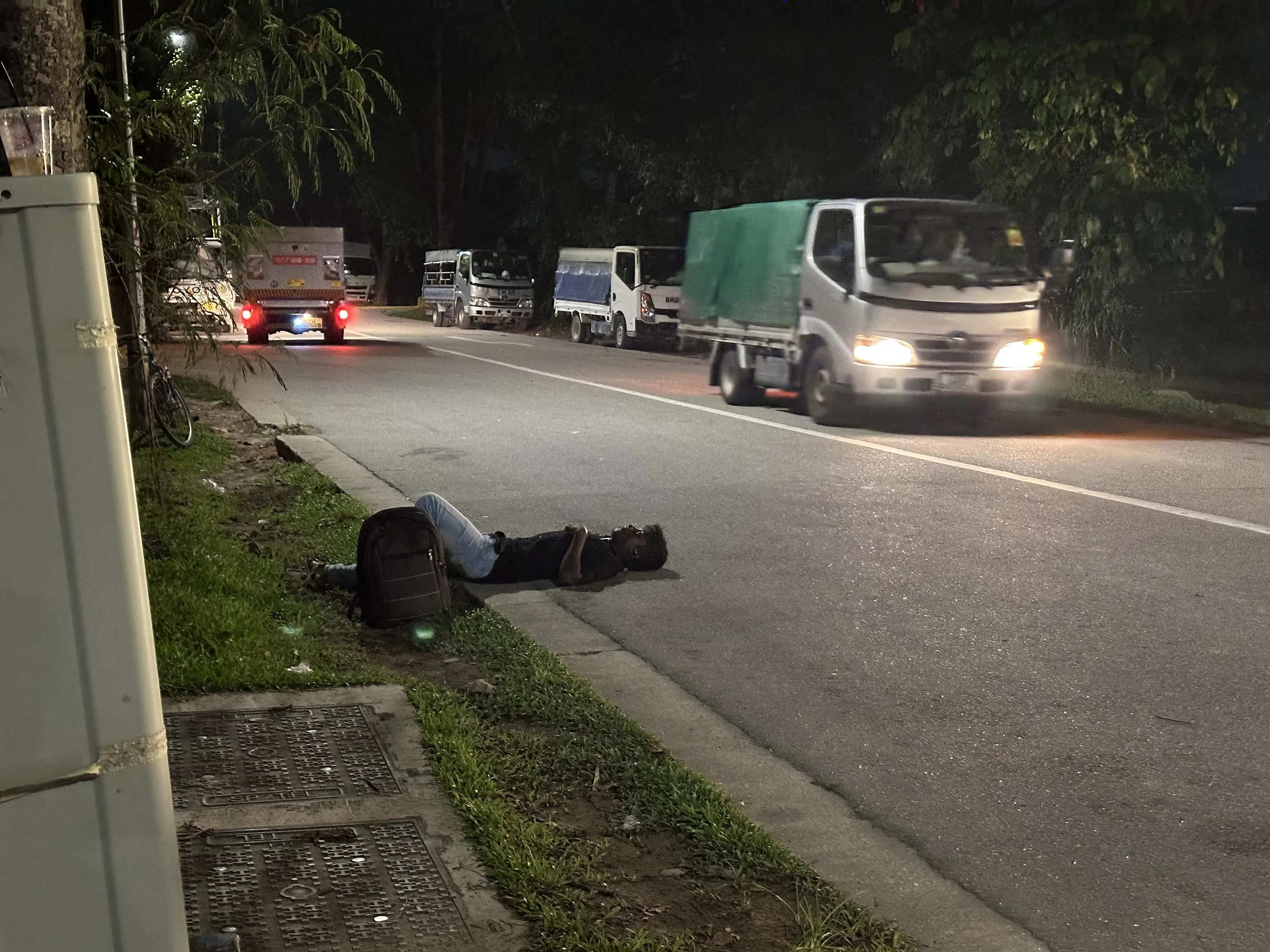 客工在路旁睡觉，罔顾来往车辆。（海峡时报）