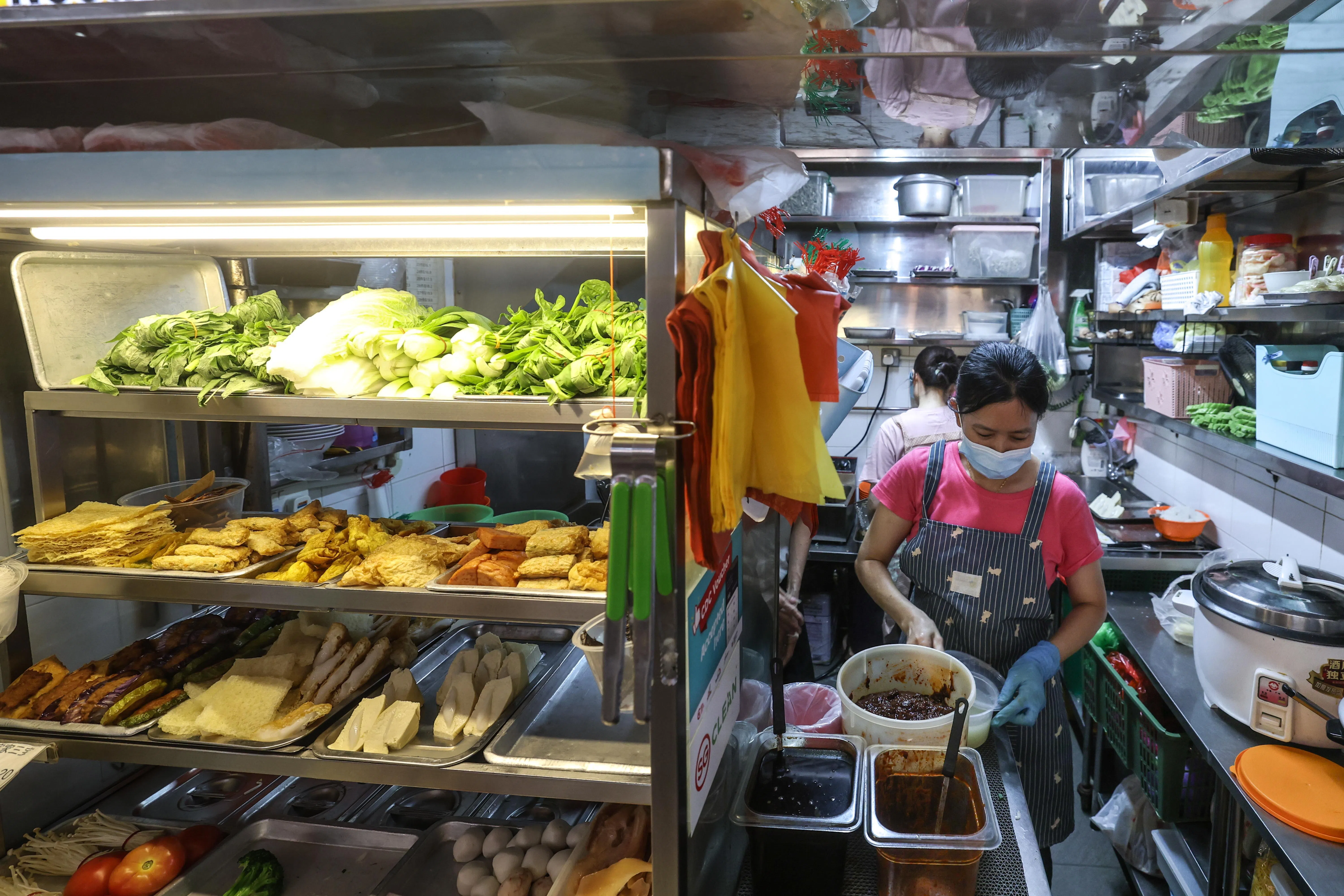 黄丽娜（前）和表妹李望一起经营酿豆腐生意，表姐妹俩很高兴如今可以自行决定是否要戴口罩，而不必担心违规。（关俊威摄）