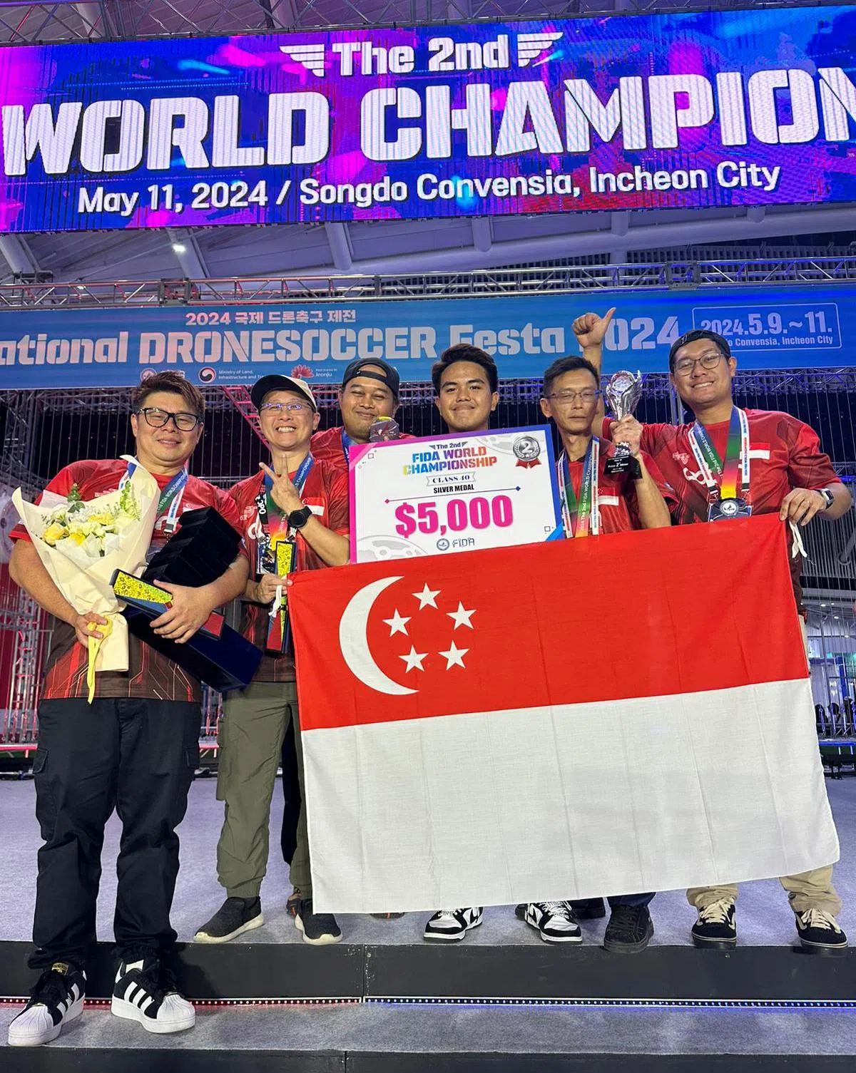 新加坡的无人机足球队到韩国仁川参加国际比赛，其中一队获得第二名的好成绩。左一为新加坡无人机足球协会主席林义德，右二为教练吴伟坤。（受访者提供）