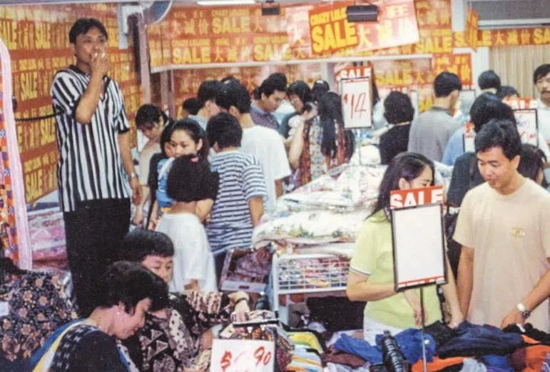 1997年，大巴窑CK百货第一天开幕，店里挤满顾客，40岁的洪振群（左），再次对着小喇叭喊“lelong”，内心百感交集。（受访者提供）