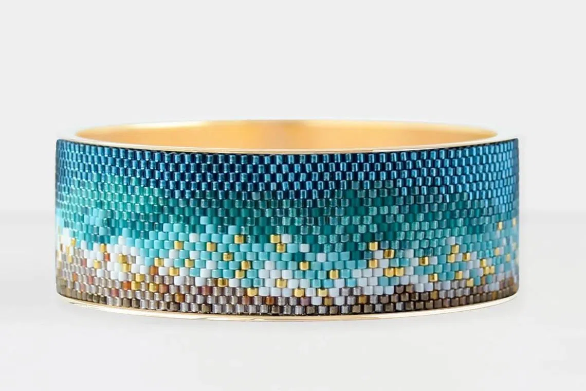首饰品牌Eden + Elie名为“海洋”的宽金手镯配色巧妙。（取自品牌官网）