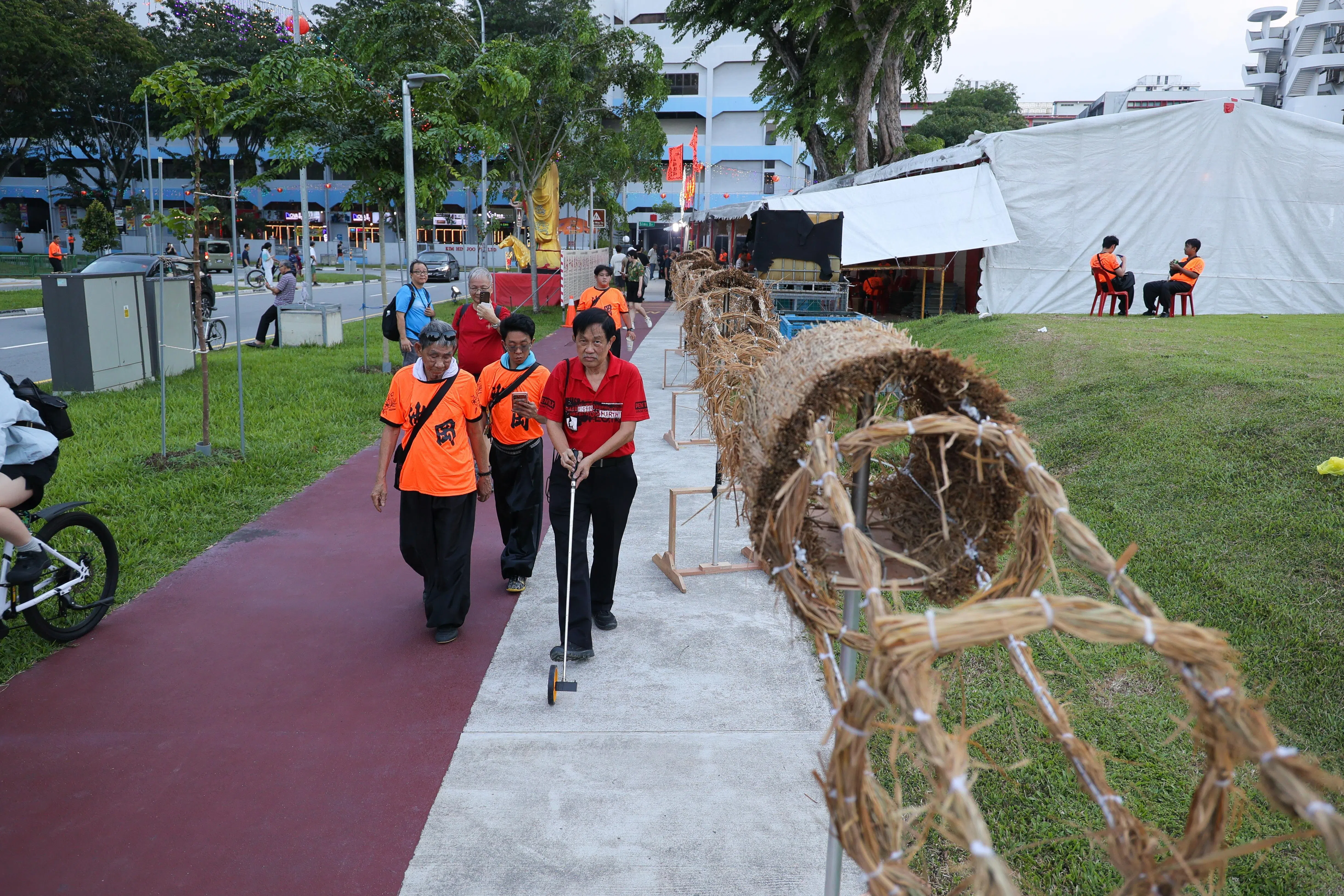 甄明仔（左）陪同新加坡纪录大全工作人员测量稻草火龙的长度。经测量，它成为本地最长的稻草火龙，并获颁证书。（张俊杰摄）