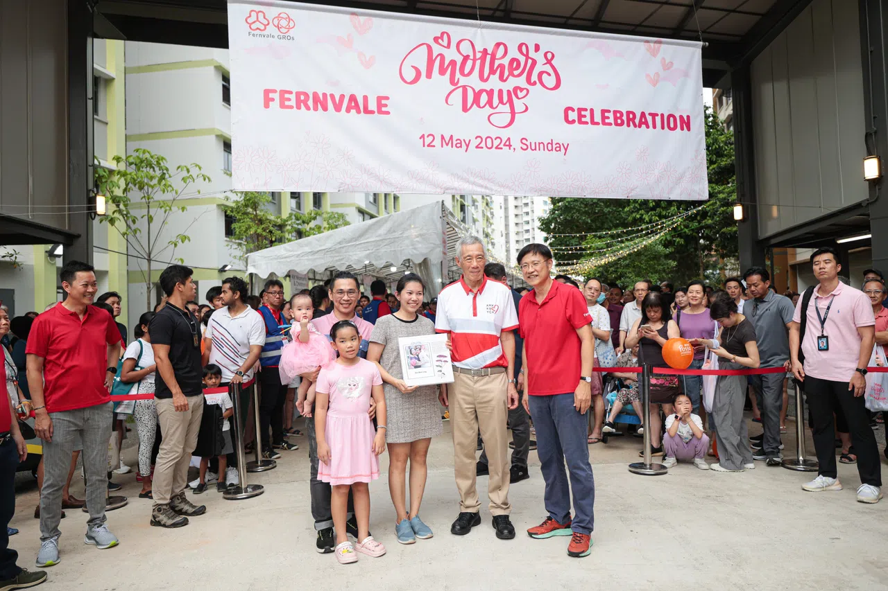 黄椀铃（中间）与丈夫和两个女儿一同参与芬维尔区的母亲节活动，并从李总理（右二）手中接过带有她提交作品的印制品。右一为宏茂桥集选区议员颜添宝。（李冠卫摄）