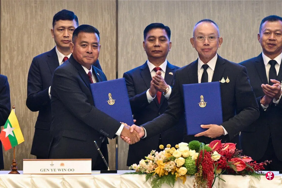 缅甸武装部队总司令耶温乌（前排左）和泰国武装部队最高司令乌克里斯（前排右），星期四在曼谷举行高级别委员会会议后握手及交换文件。 （法新社）