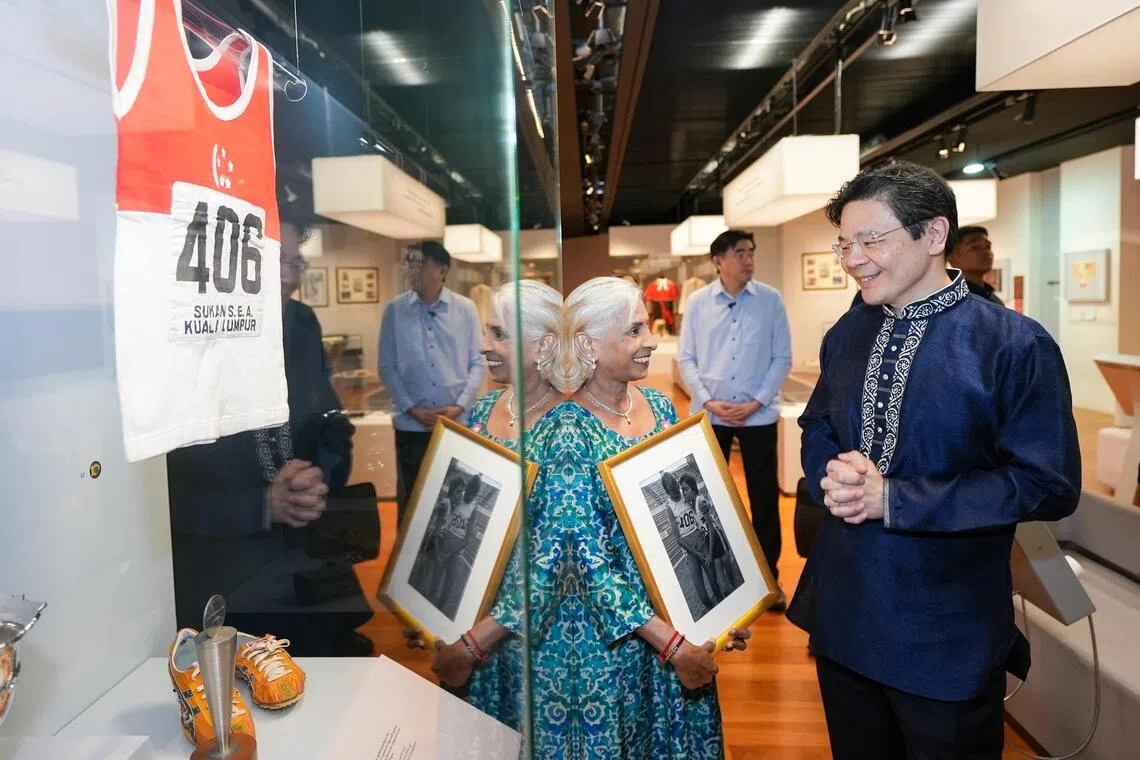 我国第一位东运会马拉松女子冠军惹耶马尼（K. Jayamani，左），将自己在赛场上穿过的衣服和跑鞋，以及获颁的最佳女运动员奖杯，借给印族文化馆展出，并向黄循财总理介绍这些展品。（淡米尔之声）