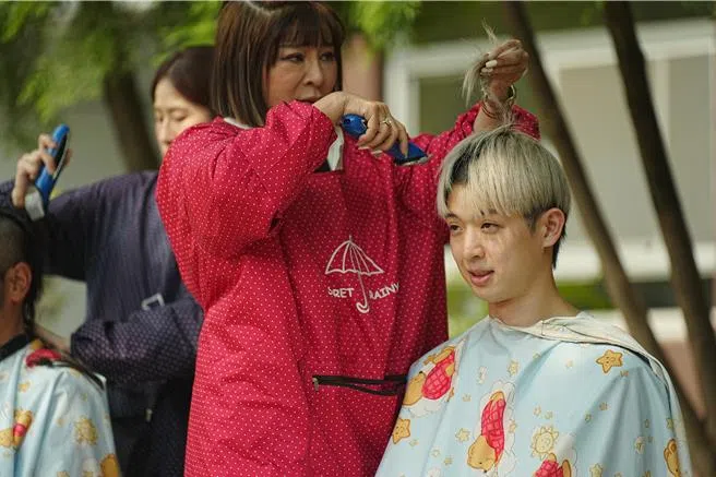 王彩桦（红衣者）充当“发婆”，为星兵林亭翰剃头。（互联网）