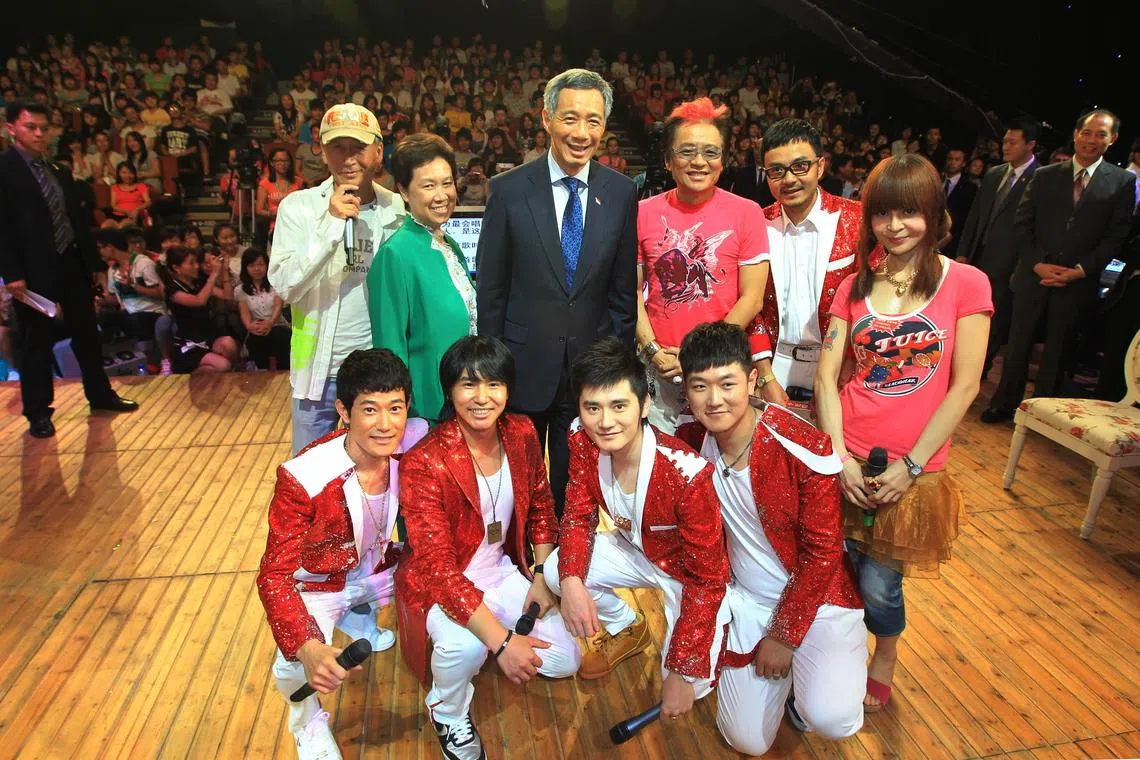 李显龙总理（后排左三）2010年9月访华时参观湖南卫视，在综艺节目《天天向上》的录制现场，同主持人和观众合影。后排左二为总理夫人何晶。（档案照片）