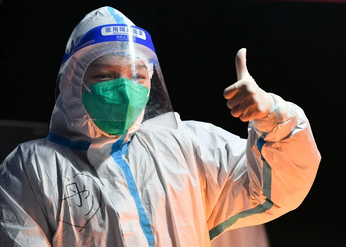 西安曲江风景线小区，一位志愿者做出加油手势。（新华社）