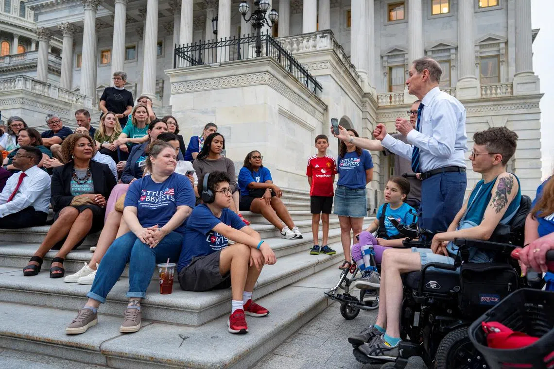 美国民主党参议员怀登（Ron Wyden，右二）星期天（6月29日）在国会大厦外，向一群将受“大而美”法案影响的美国民众讲话，表达对他们的支持，以及对这项法案的反对。（路透社）