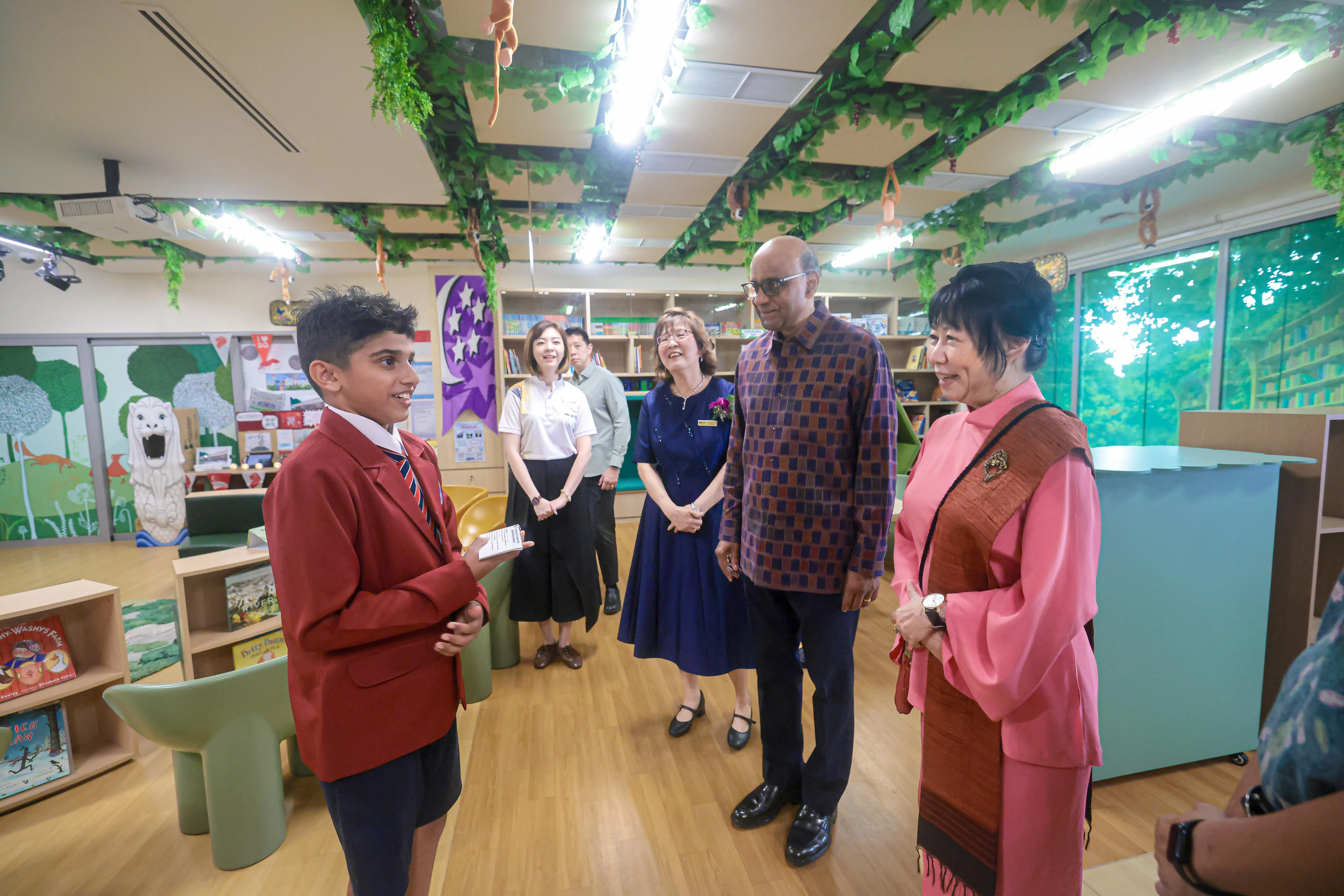 总统尚达曼（右二）和夫人珍一藤木（右一）在朝阳学校小六学生迈克尔星（Mikhel Singh，左）的带领下参观新校园的图书馆，由朝阳学校校长王惠琴（右三）陪同。图书馆以魔法森林为主题，设有不同区域，也是迈克尔星在校园里最喜欢的地方之一。（李冠卫摄）