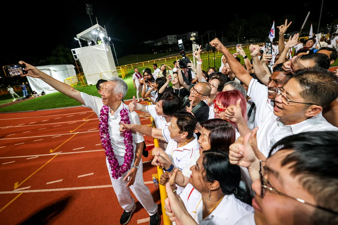 李显龙（左）在位于杨厝港体育场的行动党集合中心，与支持者自拍合影留念（叶振忠摄）