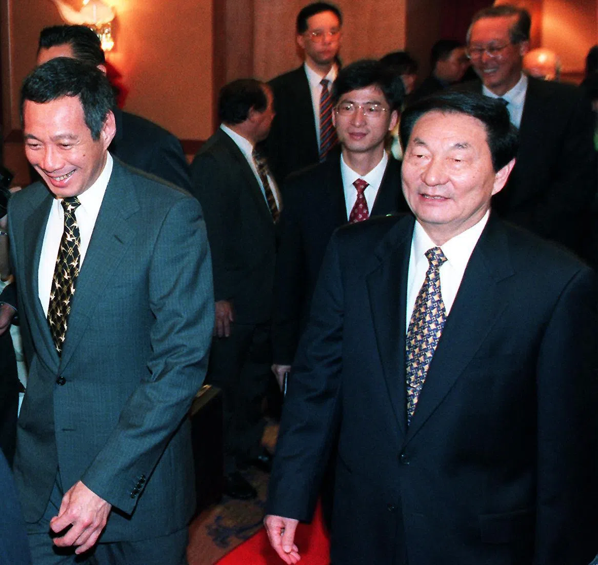 朱镕基（右）1999年11月30日访新期间，在东南亚研究院举办的第17届“新加坡讲座”上发表专题演讲，时任副总理李显龙（左）到场迎接。朱镕基后方是时任总理吴作栋。演讲后的提问时段，朱镕基答问轻松风趣，擅长以四两拨千斤的方式巧妙对应，让全场不时哄堂，更赢得阵阵热烈掌声。（商业时报）
