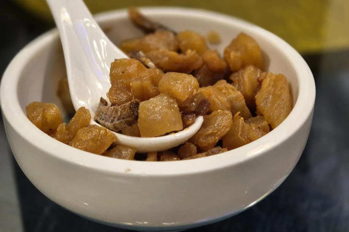 江师傅手工切丁的猪油，加入姜片和盐巴，炸至金澄香脆成猪油渣。（陈爱薇摄）