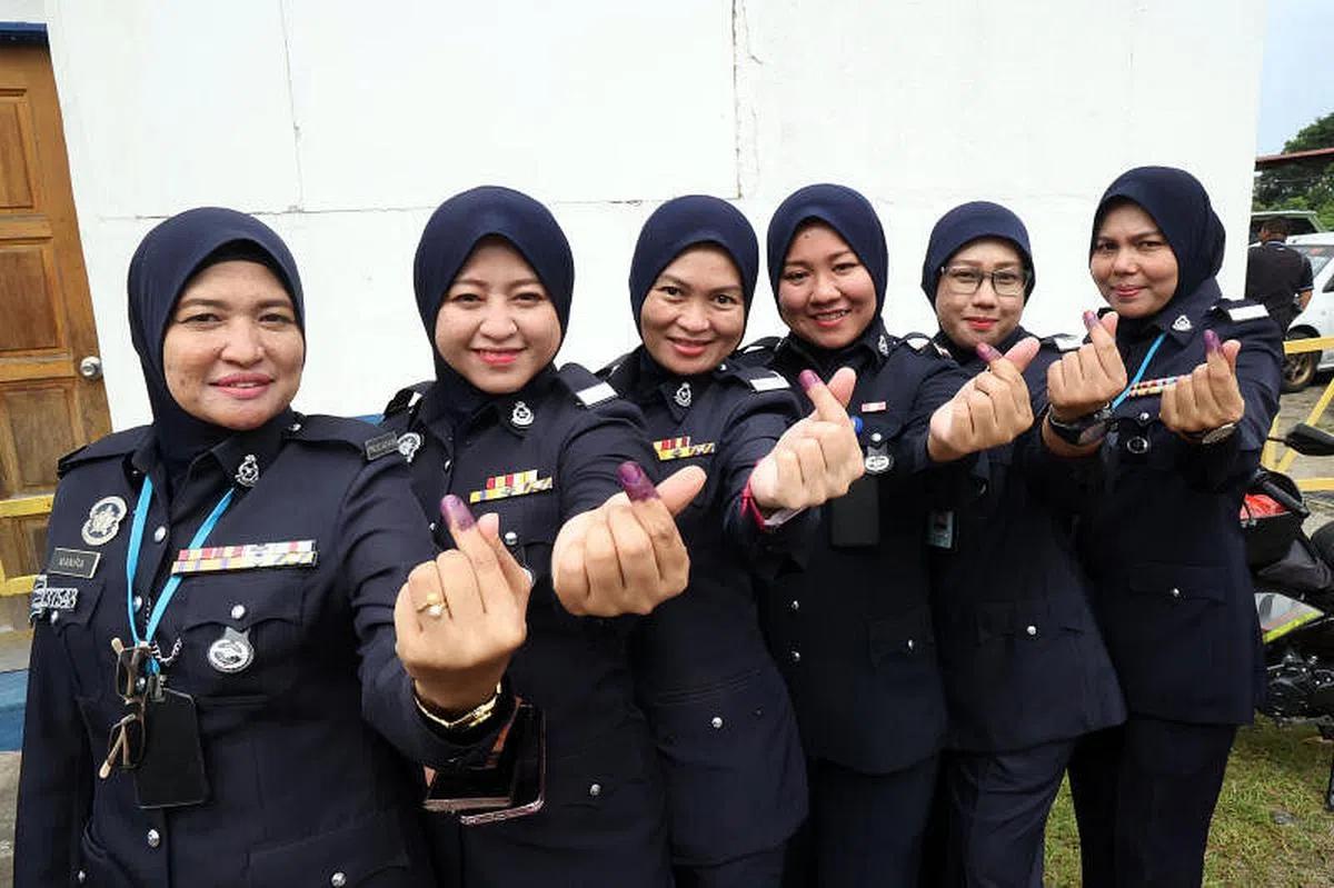 马国选举委员会这次大选仍要求所有选民投票后，左手食指必须沾染不褪色墨汁以防重复投票。图为柔佛州警察总部的女警们星期二（11月15日）上午提前投票后展示染墨食指。（邝启聪摄）