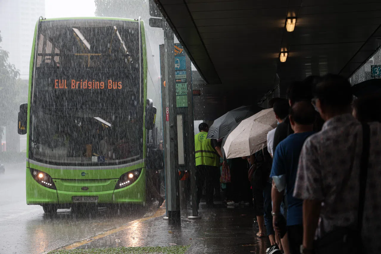 早上11时40分，波那维斯达地铁站外下着雨，公众撑伞到巴士站排队等候当局临时安排的接驳巴士。 （李冠卫摄）