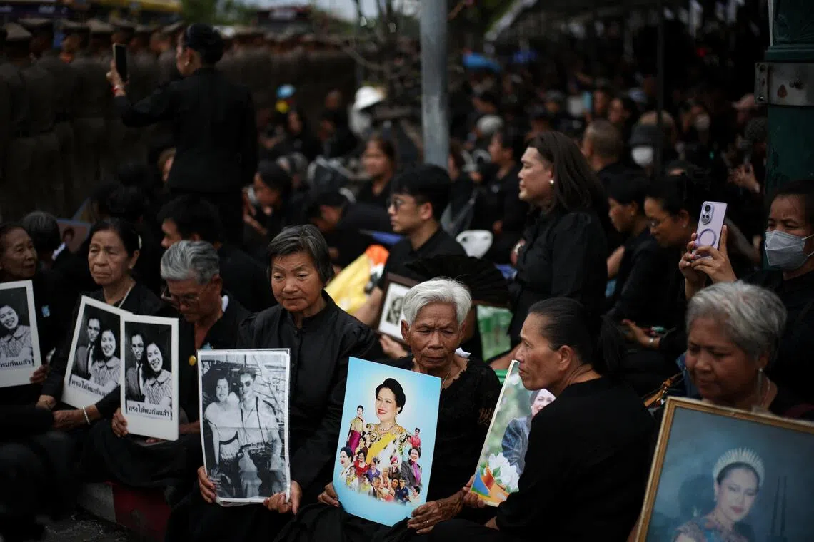 10月26日，泰国民众手捧王太后诗丽吉的照片，在灵柩车队前往曼谷大皇宫沿途等待。（路透社）