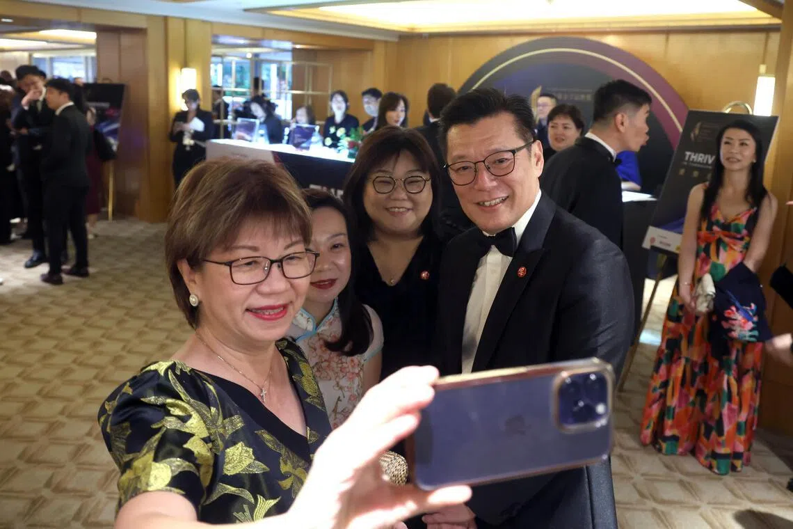 宾客拿出手机拍下这珍贵的一刻。左一是特别表扬奖得主新加坡自闭症资源中心主席兼新加坡自闭症协会会长潘丽萍，右一是《联合早报》总编辑吴新迪。（唐家鸿摄）