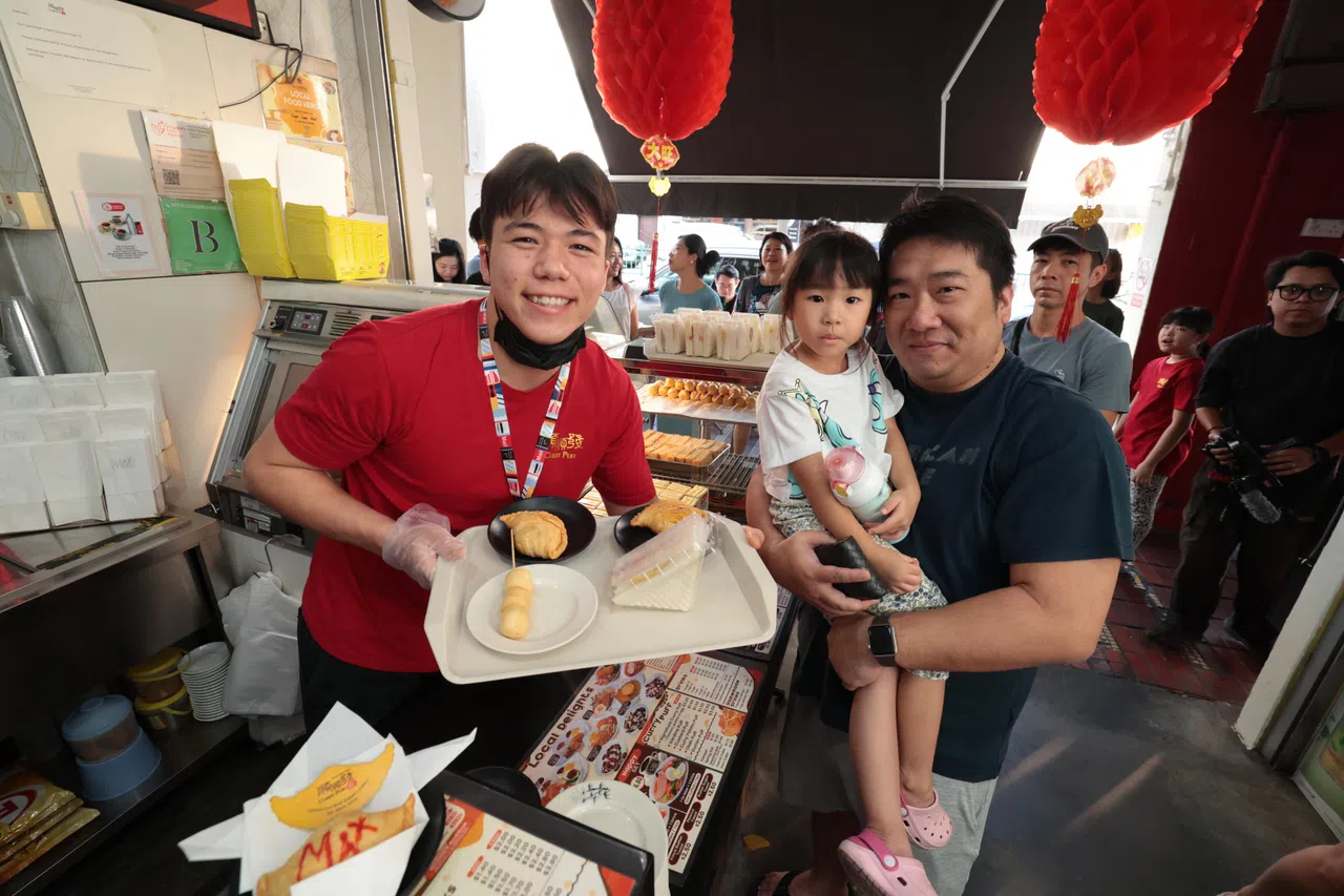 墨士廉（左）售卖咖喱卜的同时也和顾客合影留念。（梁麒麟摄）