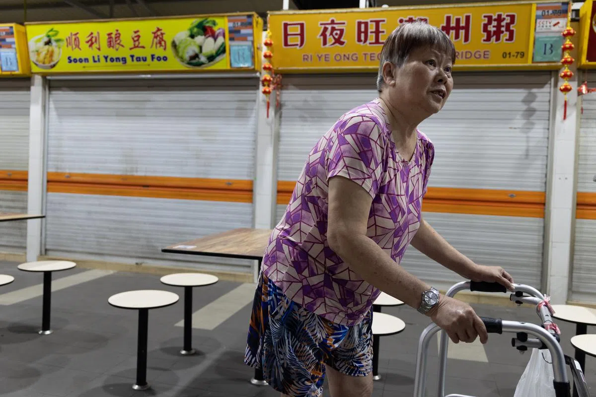 听闻吴秋发去世的消息，食客谭燕鸣（62岁，退休人士）晚上9时许拄着拐杖来到摊位前查看。（张思庆摄）