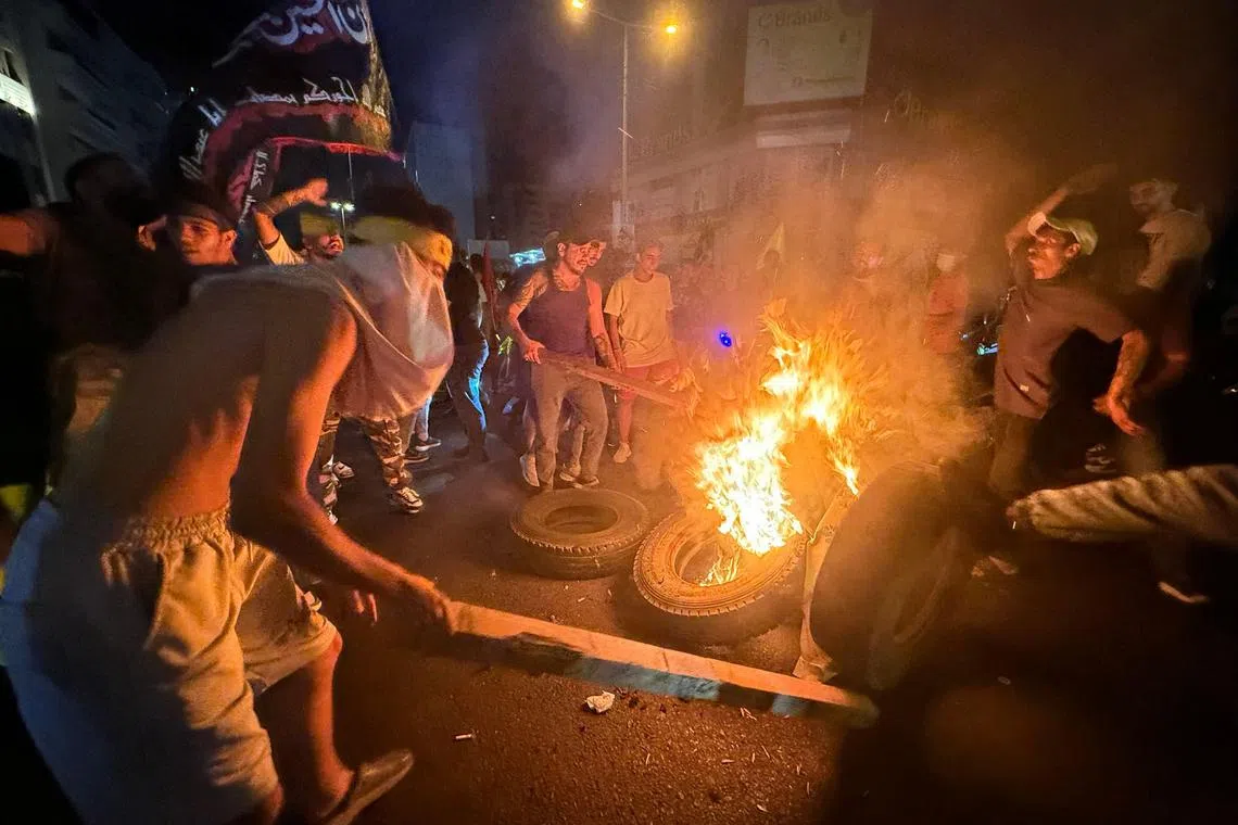 真主党支持者周四凌晨在黎巴嫩首都贝鲁特南郊焚烧轮胎封锁街道，抗议政府批准解除真主党武装的计划。（法新社）