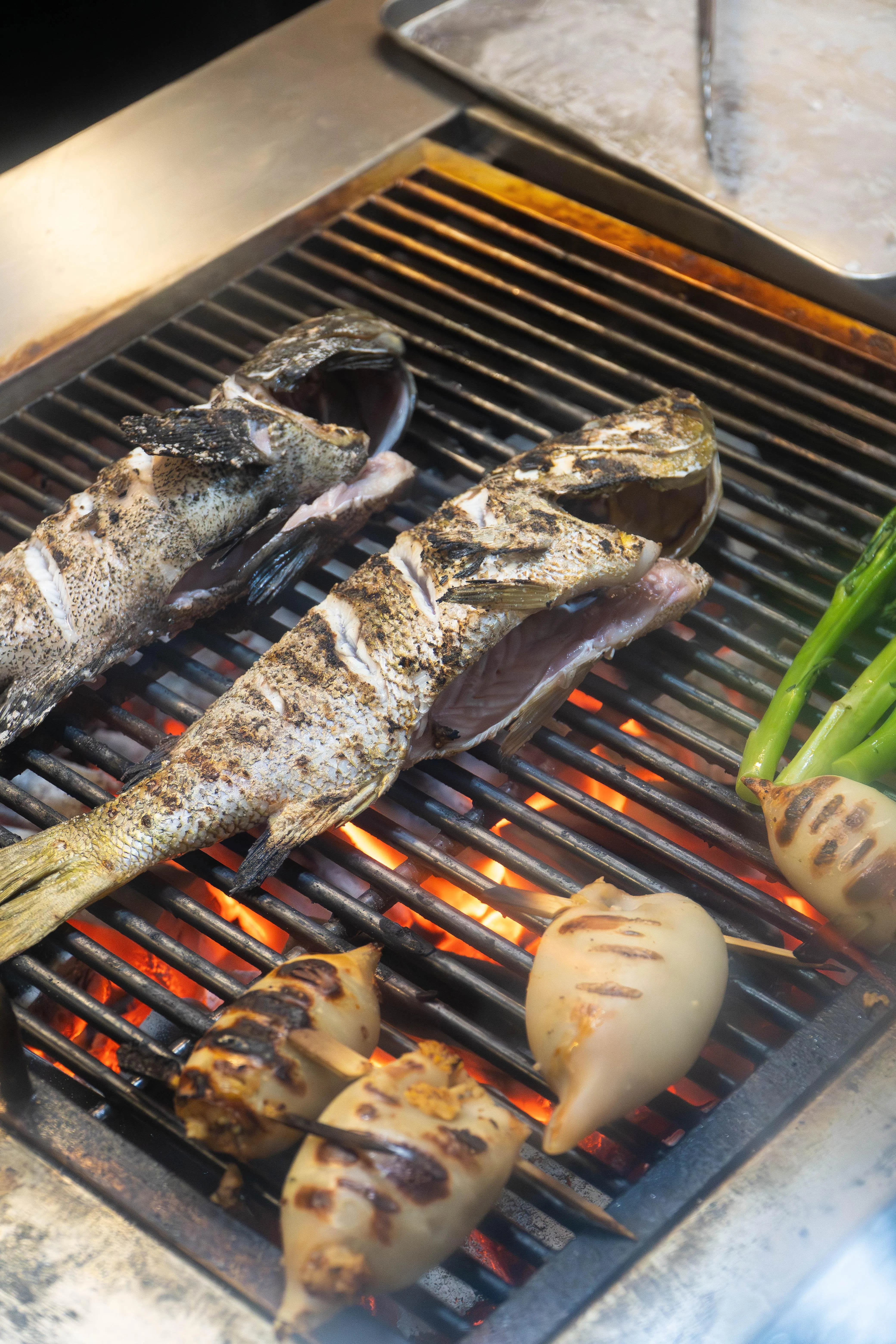 厨师用炭火烤鱼时，仅以盐和胡椒调味，保持鱼肉原汁原味。（餐馆提供）