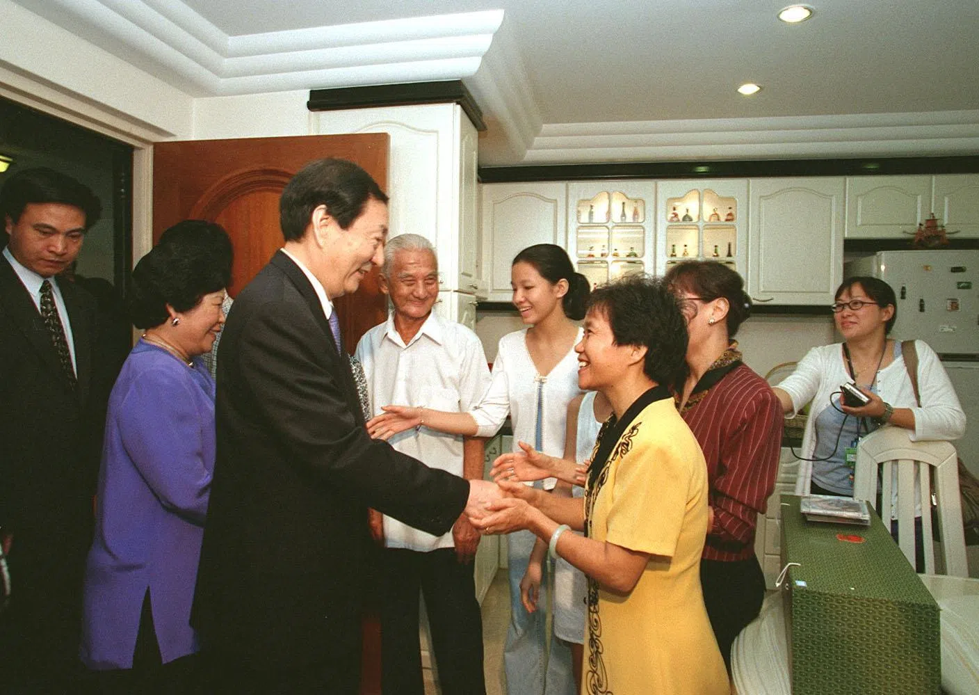 朱镕基（左三）1999年底访问我国期间，曾与夫人劳安（左二）一起参观大巴窑组屋区，并走入三户本地家庭的住家作客，了解新加坡人的日常生活。图为1999年12月1日，朱镕基在大巴窑4巷第81座组屋参观时，与其中一户单位屋主邓伟华一家人亲切互动。（档案照片）