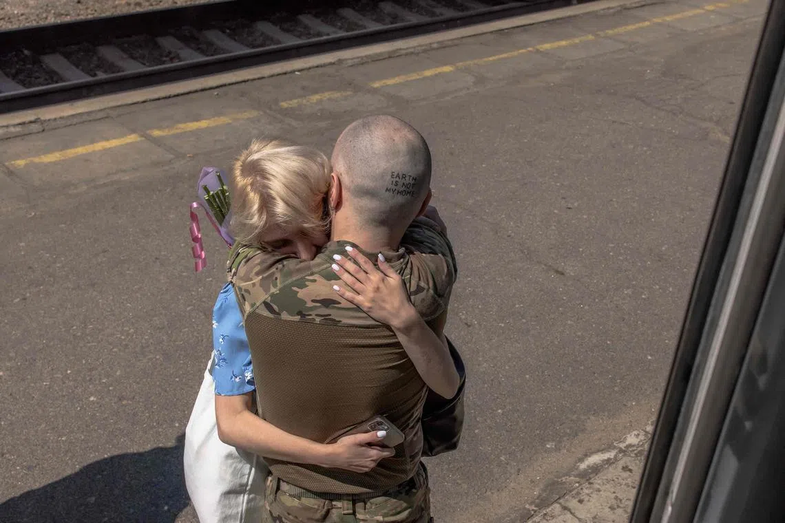 8月1日，一名准备前往战场的乌克兰军人，在顿涅茨克州的一个火车站与女友相拥道别。（法新社）