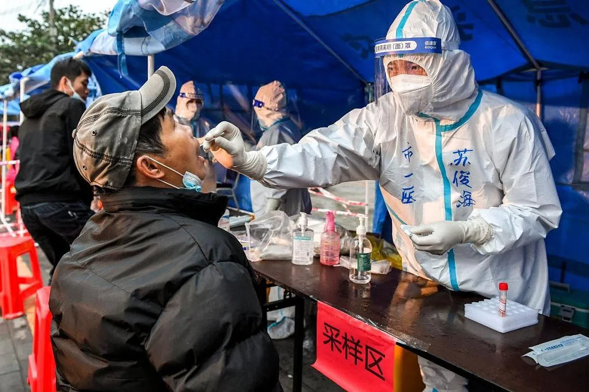 去年12月27日在东兴市中山社区核酸检测点，市民在进行核酸采样。（新华网）