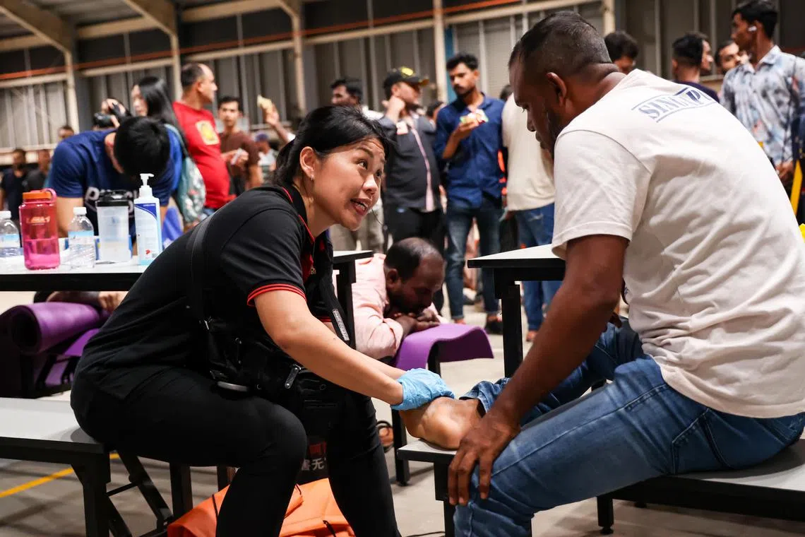 新工大保健及社会科学系助理教授林憶萍（左）一边同客工交流，一边进行物理治疗。（关俊威摄）