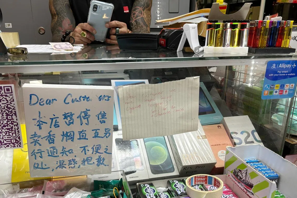 便利店内已经贴上以中英文手写的通告，声明暂停售卖香烟，但柜台旁依旧出售打火机。（何家炜摄）