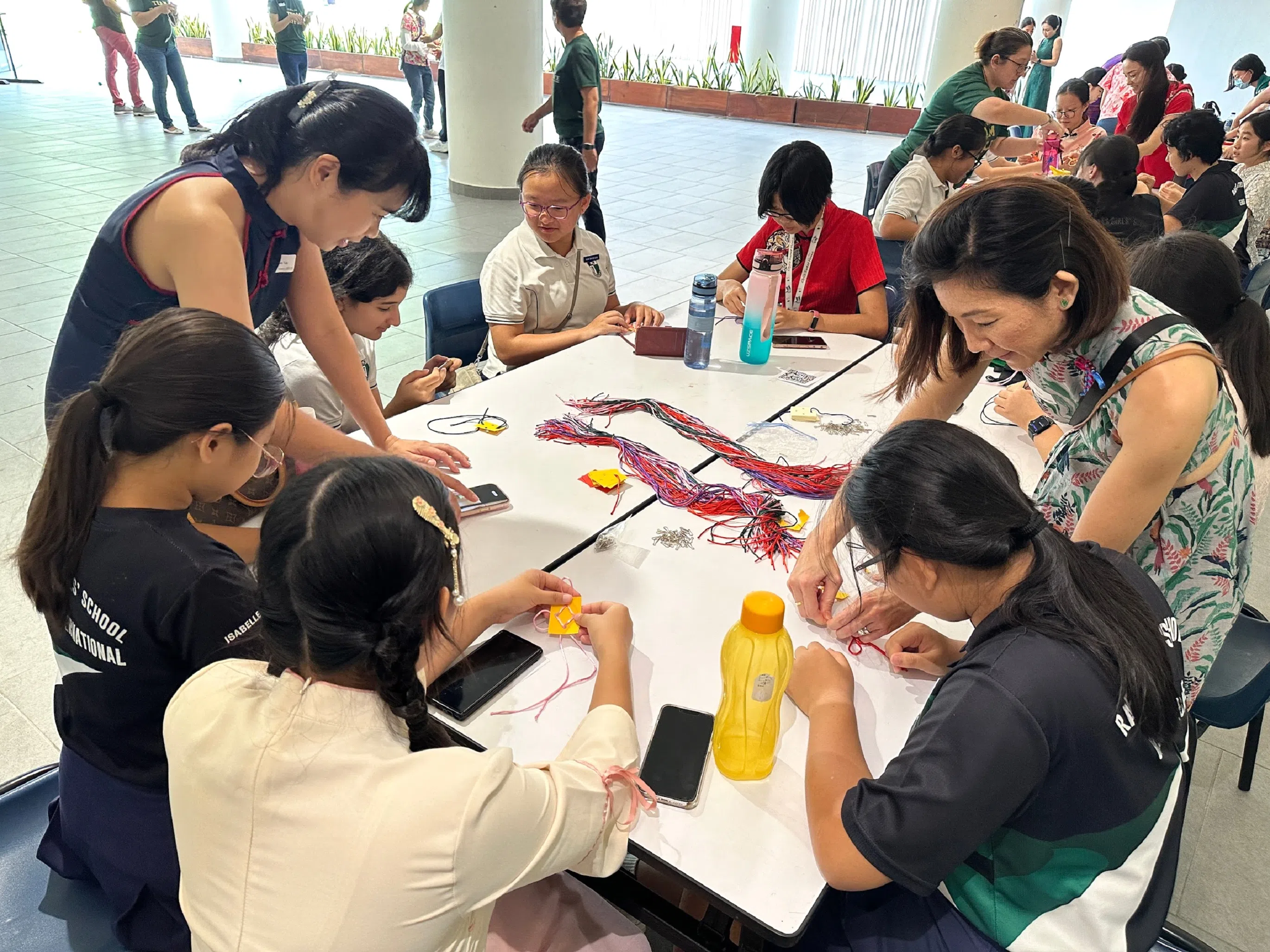 在家长义工的指导下，学生尝试制作中国结。（莱中摄影社提供）