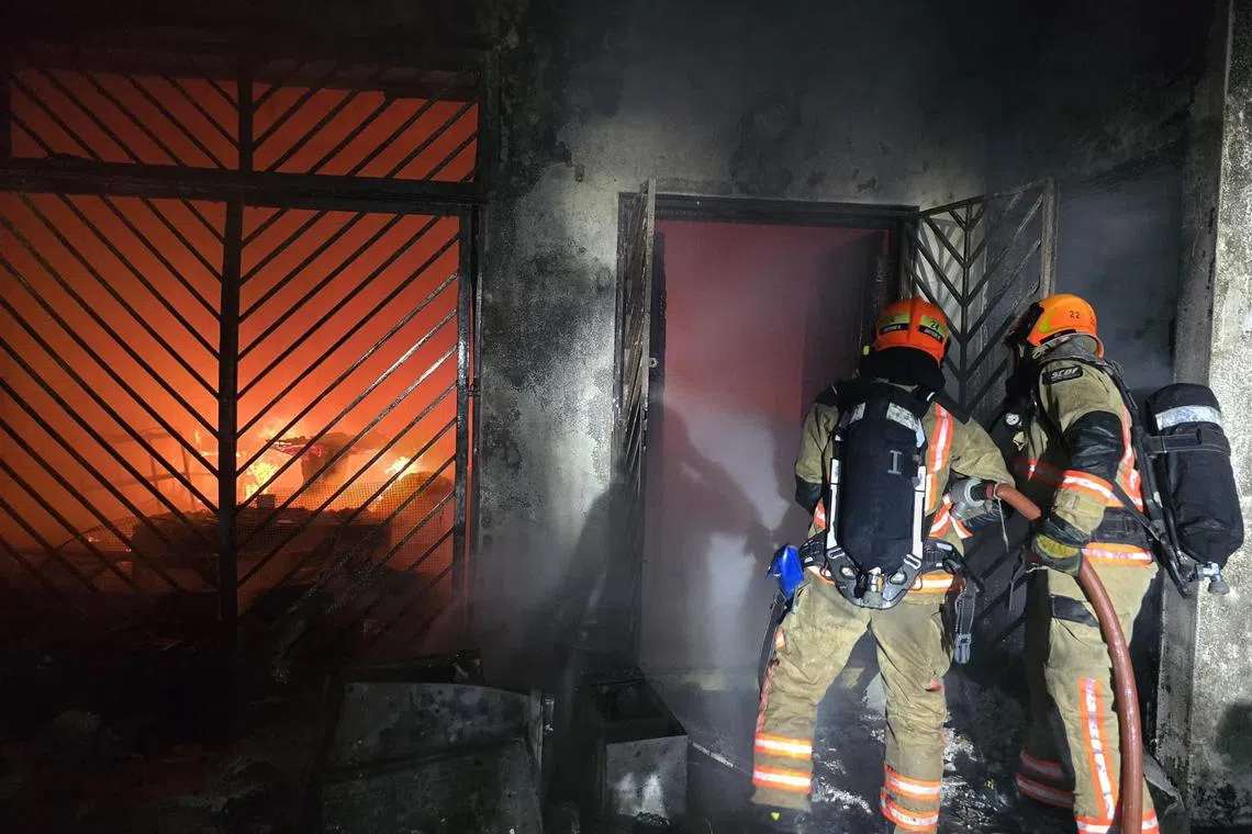 消防员破门进入火场灭火，并用两支水枪成功将火势控制下来。（取自新加坡民防部队脸书）