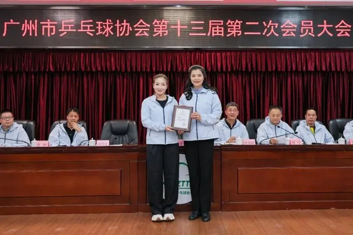 广州市体育局党组书记、局长，市体育总会主席谭爱英（右）星期五（2月13日）在广州乒协会员大会上，将委任状交给刘诗雯。（广州市乒协微信公众号）