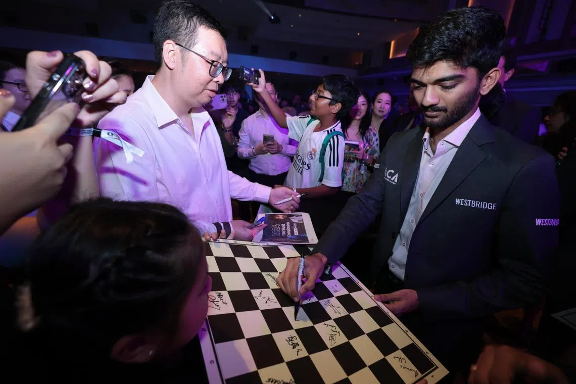 古克什（右）在棋迷的国际象棋板上签名。（梁麒麟摄）