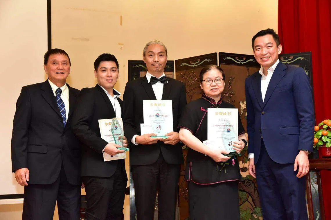 海南陈氏公会首办全国中华诗词吟唱比赛，冠军郑光辉（中）、亚军叶少玲（右二）、季军林家豪（左二）从文化、社区及青年部兼社会及家庭发展部高级政务次长蔡瑞隆（右一）和海南陈氏公会会长陈嘉兆（左一）手中接过奖金与奖杯。（档案照）