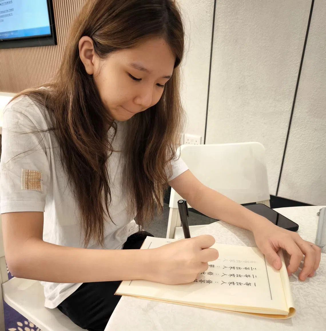 懂事的吴绚茹专心替妈妈抄完经文。（钟雁龄摄）