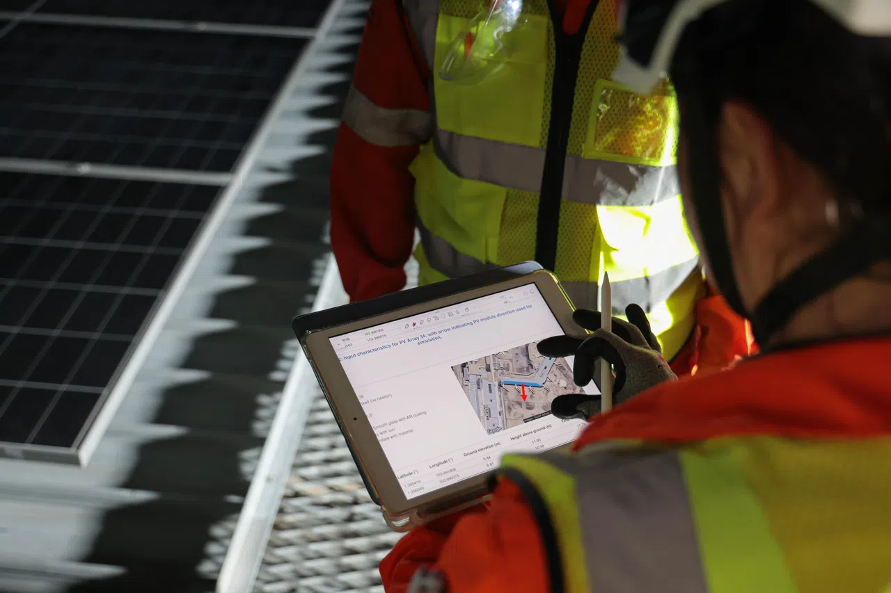 安装团队用平板电脑向记者解释，如何通过模拟确保太阳能板不会造成眩光等影响。（李冠卫摄）