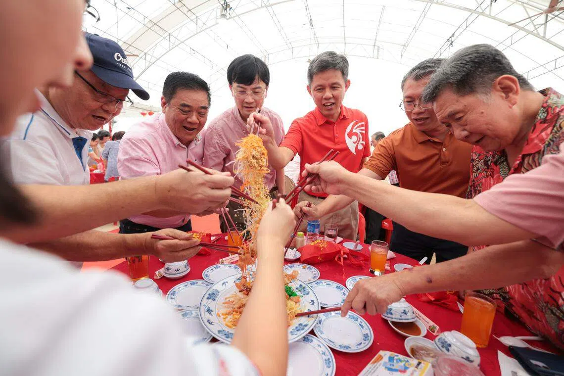 出席丹戎巴葛区和拉丁马士区新春团拜联欢午宴的教育部长陈振声（右三），与其他基层组织顾问及居民一起捞鱼生。（李冠卫摄）
